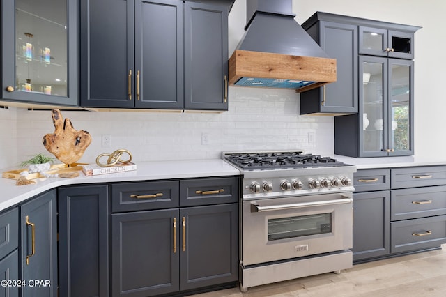 kitchen with light countertops, high end stove, custom range hood, and backsplash