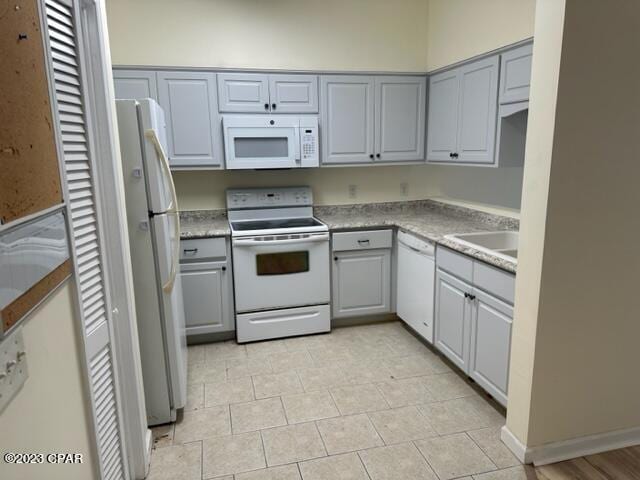 kitchen featuring gray cabinets, sink, light tile patterned floors, and white appliances