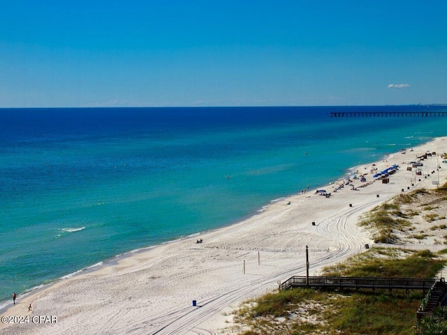 property view of water featuring fence and a beach view