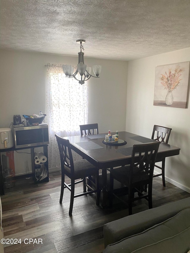 dining area with a notable chandelier, wood-type flooring, and a textured ceiling