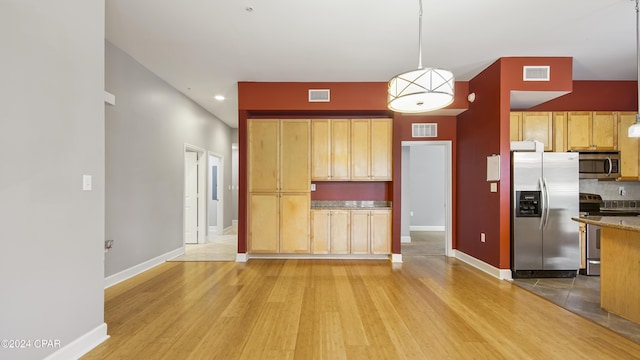 kitchen featuring decorative light fixtures, decorative backsplash, light brown cabinetry, appliances with stainless steel finishes, and light wood-type flooring