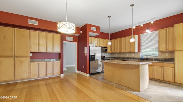 kitchen with decorative light fixtures, a center island, stainless steel appliances, and light hardwood / wood-style floors