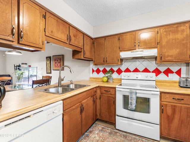 kitchen featuring decorative backsplash, white appliances, a textured ceiling, and sink