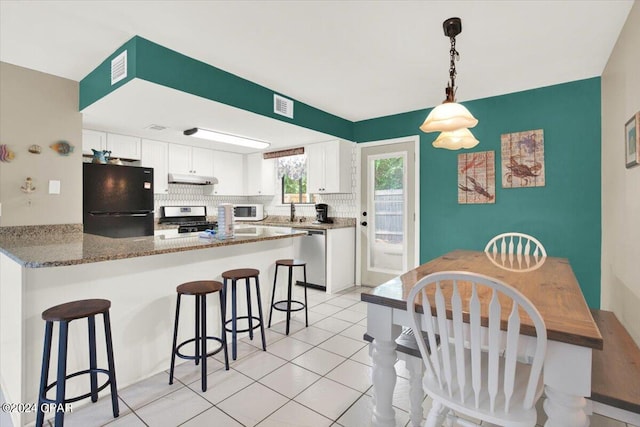 kitchen with range, white cabinets, black fridge, and tasteful backsplash