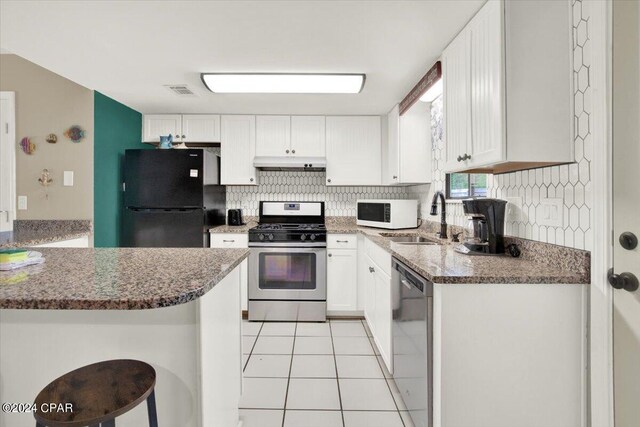 kitchen featuring appliances with stainless steel finishes, decorative backsplash, sink, white cabinets, and light tile patterned floors