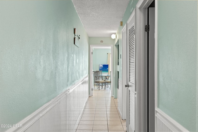 corridor with a textured ceiling and light tile patterned floors