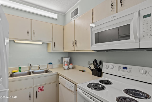 kitchen featuring sink, a textured ceiling, cream cabinetry, and white appliances