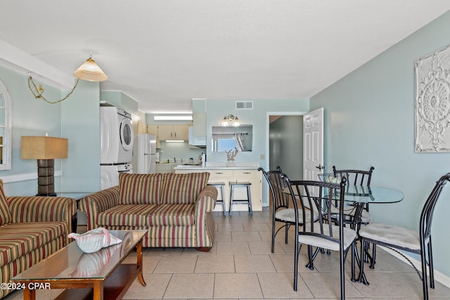 living room with light tile patterned flooring and stacked washing maching and dryer