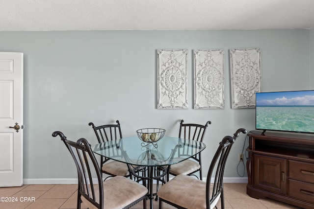 dining space featuring light tile patterned flooring and a textured ceiling