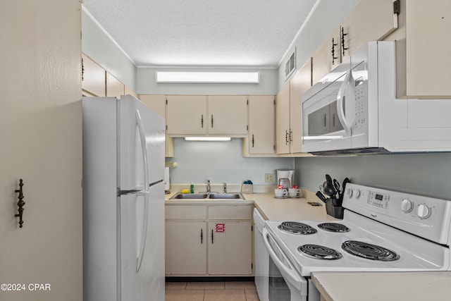 kitchen with white appliances, light tile patterned floors, a textured ceiling, cream cabinets, and sink