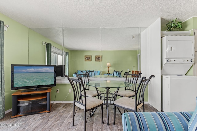 dining room with stacked washing maching and dryer, a textured ceiling, and light hardwood / wood-style floors