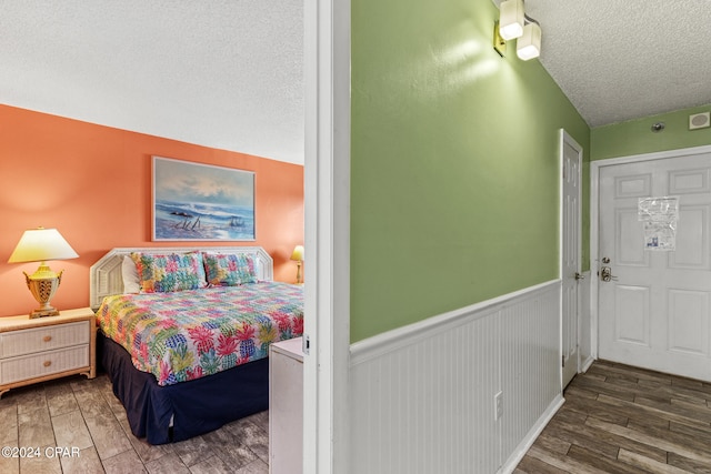 bedroom featuring hardwood / wood-style flooring, vaulted ceiling, and a textured ceiling