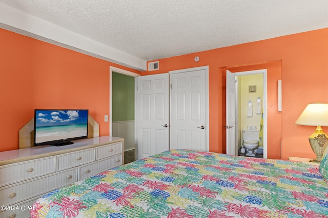 bedroom with ensuite bathroom and a textured ceiling