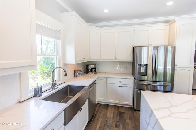 kitchen with appliances with stainless steel finishes, backsplash, sink, light stone countertops, and dark hardwood / wood-style flooring