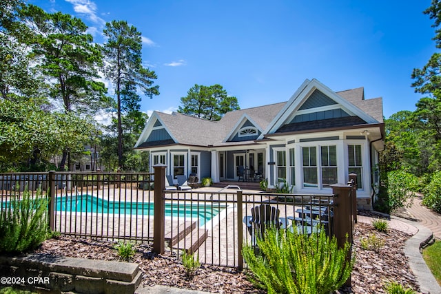 rear view of property featuring a fenced in pool and a patio area