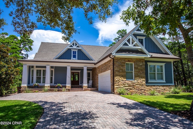 craftsman inspired home featuring a garage, a front lawn, and a porch