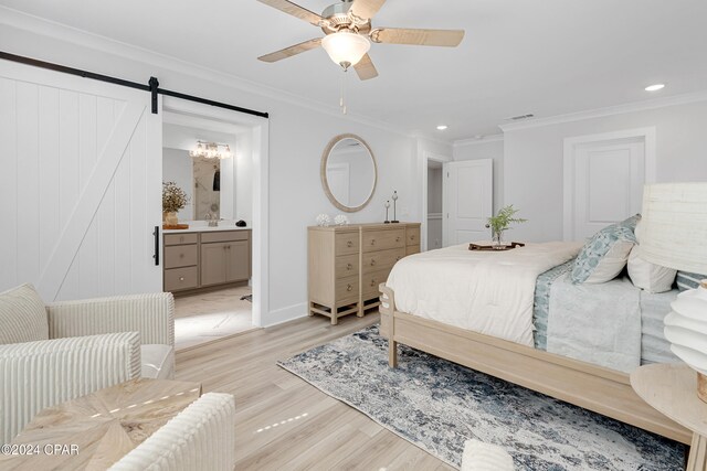 bedroom featuring crown molding, ensuite bath, ceiling fan, a barn door, and light wood-type flooring