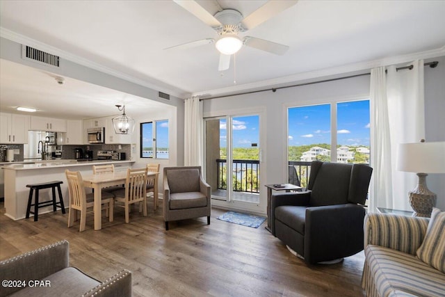 living room featuring hardwood / wood-style flooring, ceiling fan, ornamental molding, and sink