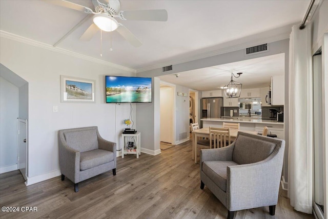 sitting room featuring ceiling fan with notable chandelier, light hardwood / wood-style floors, and crown molding