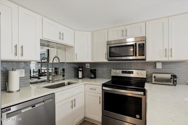 kitchen with decorative backsplash, stainless steel appliances, white cabinetry, and sink