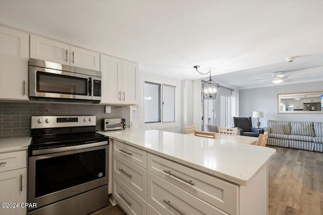 kitchen featuring white cabinetry, light hardwood / wood-style flooring, backsplash, kitchen peninsula, and appliances with stainless steel finishes