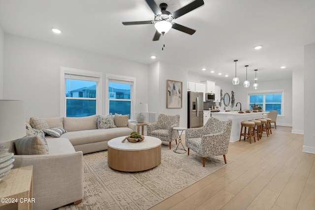 living room with ceiling fan, light hardwood / wood-style floors, and sink