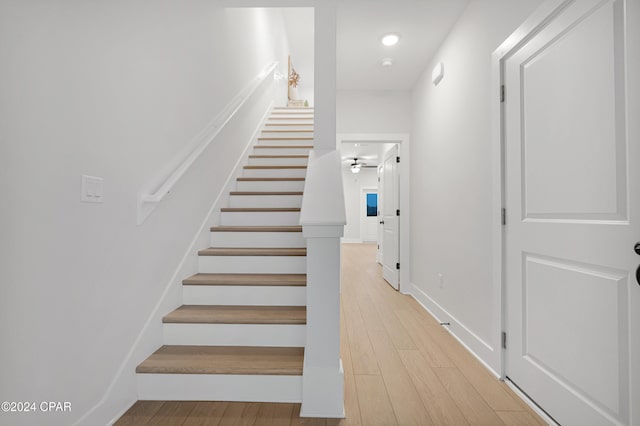 stairway with ceiling fan and wood-type flooring