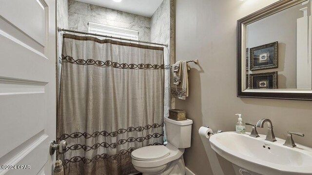 bathroom featuring toilet, sink, and walk in shower