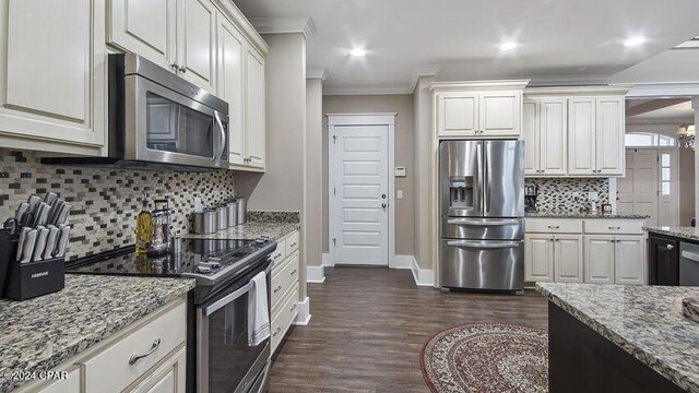 kitchen featuring light stone countertops, appliances with stainless steel finishes, dark hardwood / wood-style floors, tasteful backsplash, and ornamental molding