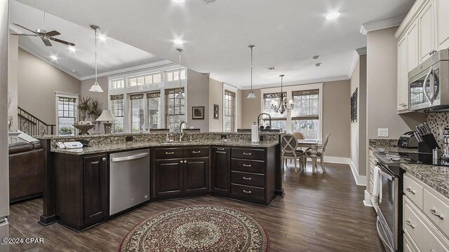 kitchen with ceiling fan with notable chandelier, a wealth of natural light, stainless steel appliances, and white cabinetry