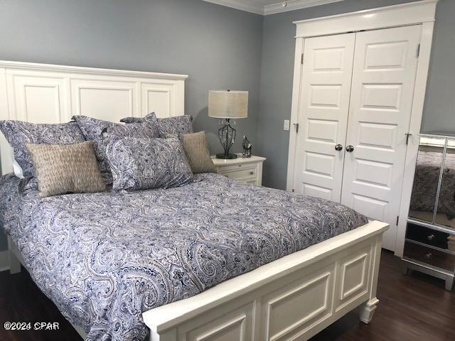 bedroom with crown molding, dark hardwood / wood-style floors, and a closet