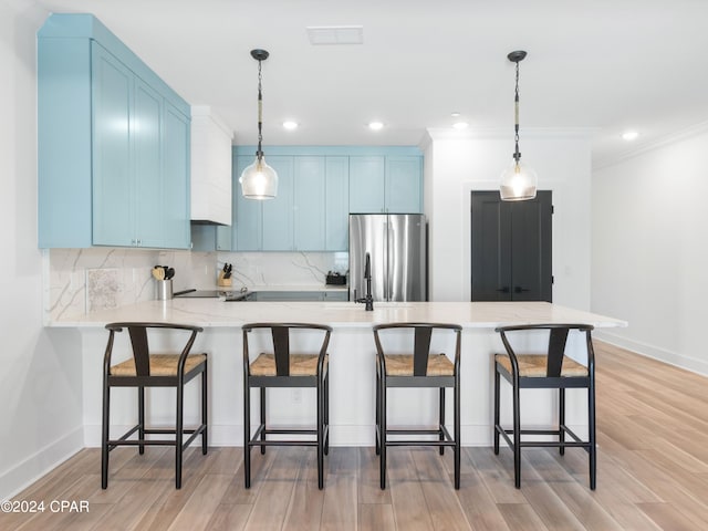 kitchen featuring stainless steel refrigerator, a breakfast bar, light wood-type flooring, and blue cabinets