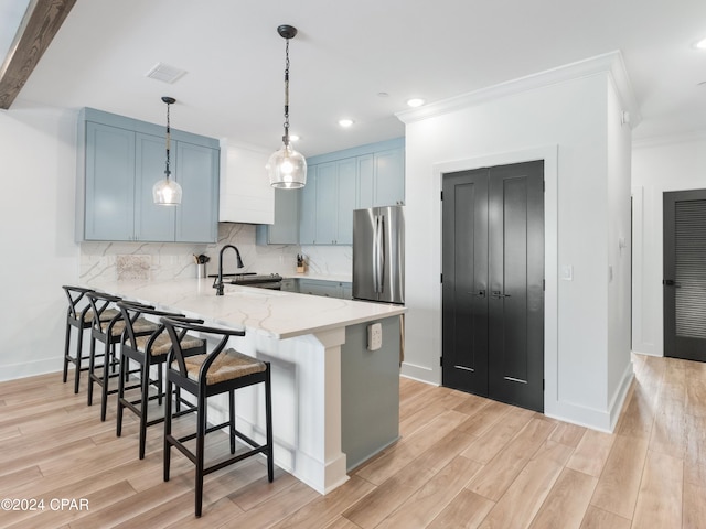 kitchen featuring light hardwood / wood-style floors, kitchen peninsula, stainless steel fridge, and light stone counters