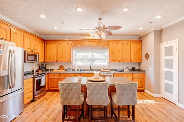 244 E 3rd Pl, Panama City, FL 32401 - kitchen with light wood-style flooring, a sink, crown molding, a kitchen island, and stainless steel appliances