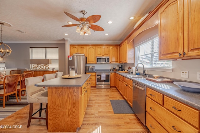 244 E 3rd Pl, Panama City, FL 32401 - kitchen featuring ornamental molding, light wood finished floors, a sink, a kitchen bar, and stainless steel appliances