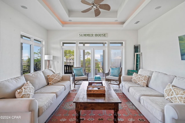 living room with a tray ceiling and ceiling fan