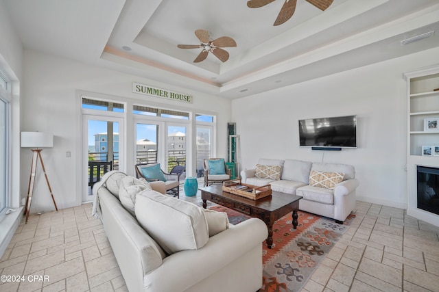 living room featuring a raised ceiling and ceiling fan