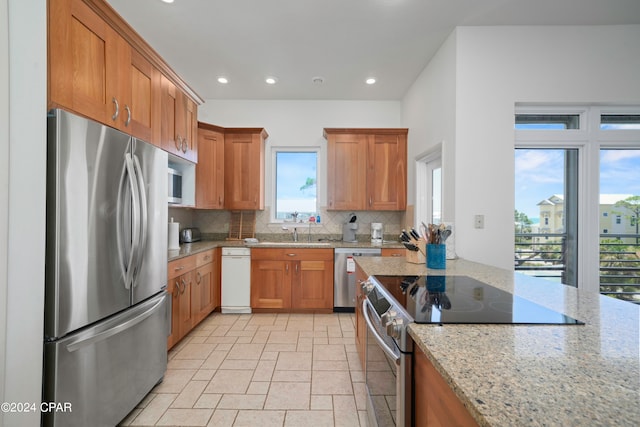 kitchen featuring sink, light stone countertops, stainless steel appliances, and tasteful backsplash