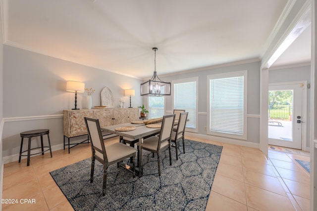 tiled dining space featuring ornamental molding and a chandelier