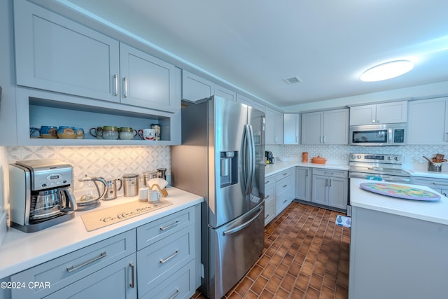 kitchen with appliances with stainless steel finishes, gray cabinetry, and tasteful backsplash