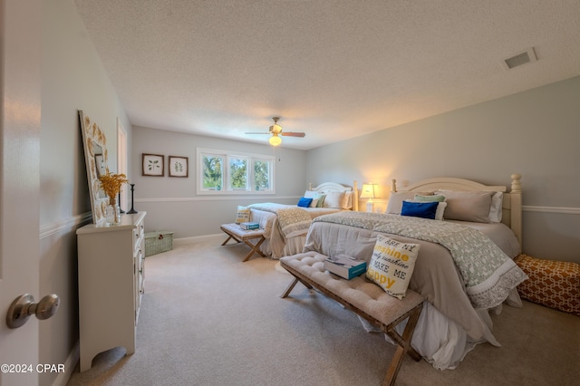 bedroom featuring ceiling fan, a textured ceiling, and light colored carpet