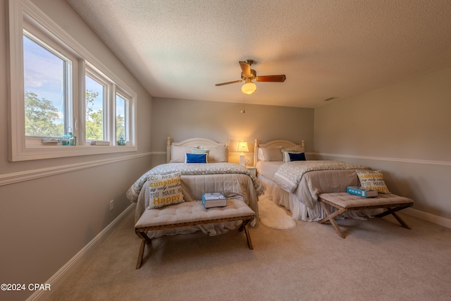 carpeted bedroom with ceiling fan and a textured ceiling