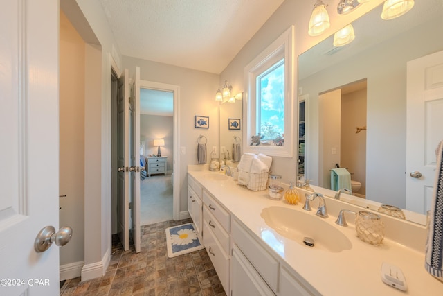 bathroom featuring a textured ceiling, vanity, and toilet