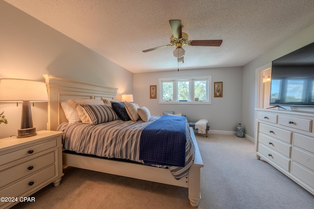 bedroom with a textured ceiling, light colored carpet, and ceiling fan