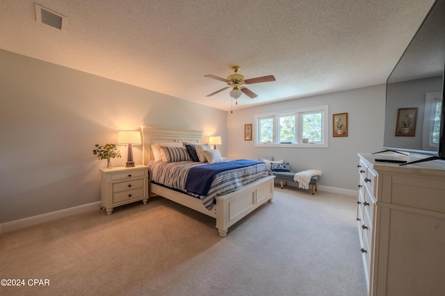 carpeted bedroom with ceiling fan and a textured ceiling