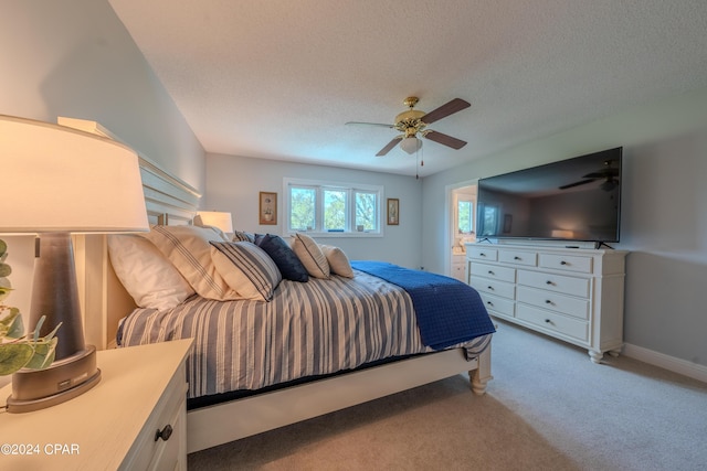 carpeted bedroom featuring ceiling fan and a textured ceiling