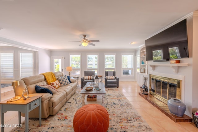 living room with ornamental molding, light tile patterned floors, built in shelves, and ceiling fan