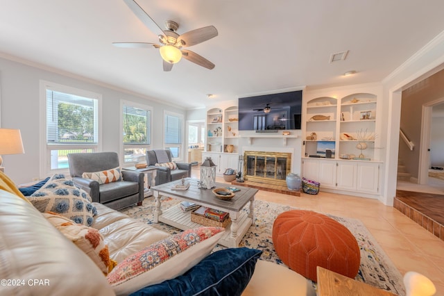 living room featuring light tile patterned floors, crown molding, and built in shelves