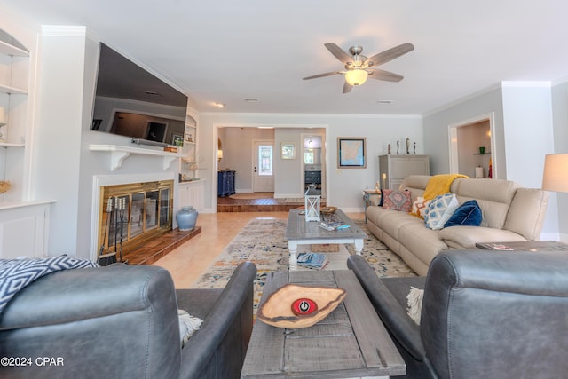 living room featuring ornamental molding, built in shelves, and ceiling fan