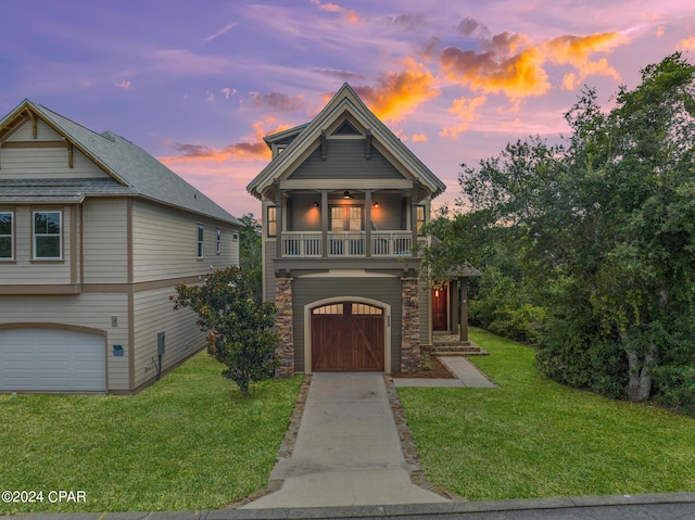 view of front of home with a lawn, a balcony, ceiling fan, and a garage